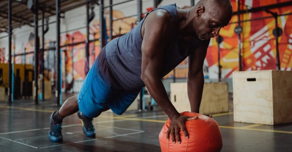 An athletic man doing push-ups on a medicine ball in a colorful gym setting.